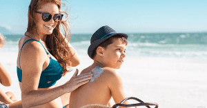 Mother applying sunscreen to her son at the beach